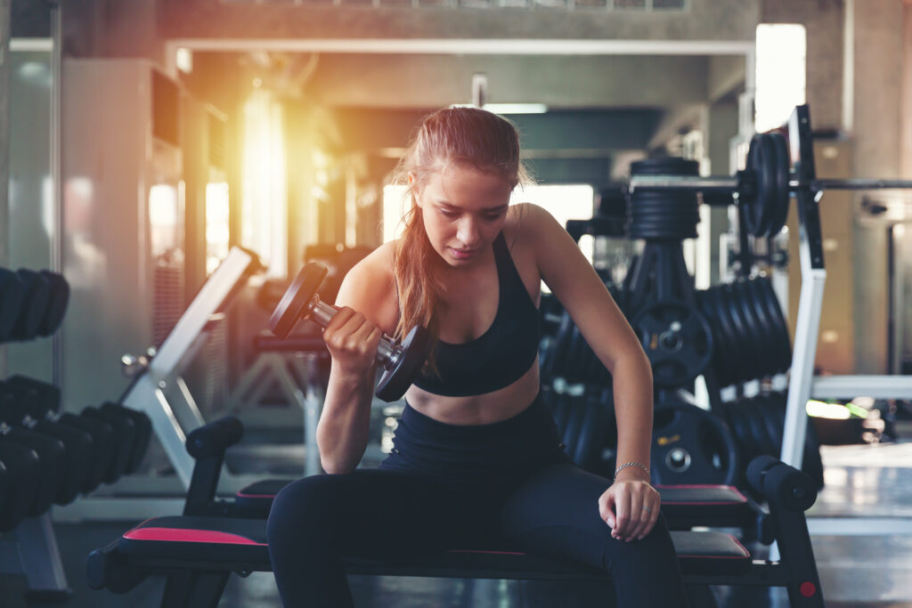 Donna in palestra mentre esegue curl con manubrio per tonificare le braccia.