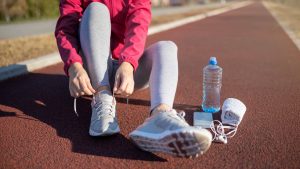 Donna sportiva che si allaccia le scarpe su una pista da corsa
